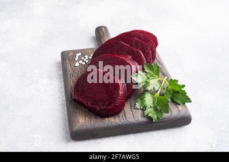 Slices of boiled beetroot on a cutting Board with parsley leaves on a wooden rustic background. Copy space, Stock Photo