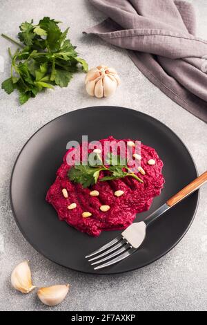 Salad of grated beetroot pine nuts and parsley with cream sauce on a plate Stock Photo