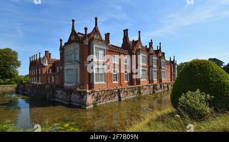 Helmingham Hall with moat, trees blue sky  and reflections. Stock Photo