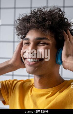 Pleased african american guy in earphones working with laptop while ...