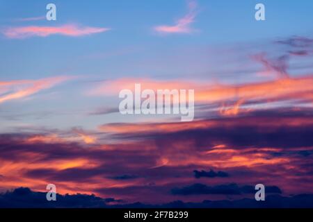 A colorful sky at sunset with clouds painted in many shades from pink to black Stock Photo