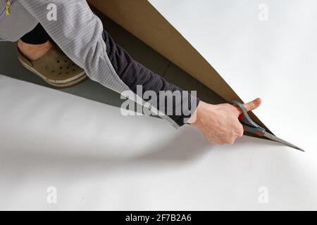 A female artist cutting canvas to prepare her own picture supports. Stock Photo