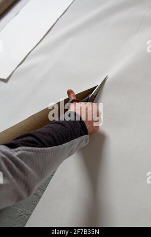 A female artist cutting canvas to prepare her own picture supports. Stock Photo