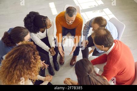 High angle shot of diverse group of people talking in therapy session or business meeting Stock Photo
