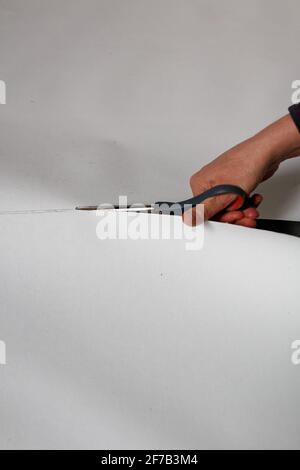 A female artist cutting canvas to prepare her own picture supports. Stock Photo