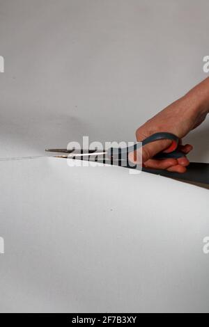 A female artist cutting canvas to prepare her own picture supports. Stock Photo