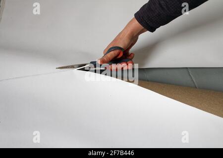 A female artist cutting canvas to prepare her own picture supports. Stock Photo