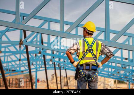 Engineer technician watching warehouse steel roof structure , Engineer technician Looking Up and Analyzing an Unfinished Construction Project. Stock Photo