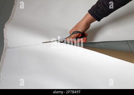 A female artist cutting canvas to prepare her own picture supports. Stock Photo