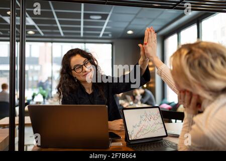Female coworkers doing high five in cafe Stock Photo