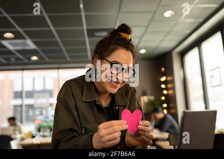 Smiling woman in cafe holding paper heart Stock Photo