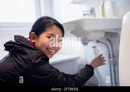 Smiling woman fixing bathroom sink Stock Photo