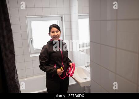 Smiling woman fixing bathroom sink Stock Photo