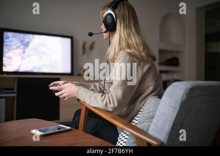 Young woman with headset playing video game Stock Photo