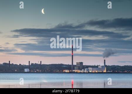 Aghada, Cork, Ireland. 06th April, 2021. A waning Moon begining to rise before dawn over the ESB generating station in Aghada, Co. Cork, Ireland. - Credit; David Creedon / Alamy Live News Stock Photo