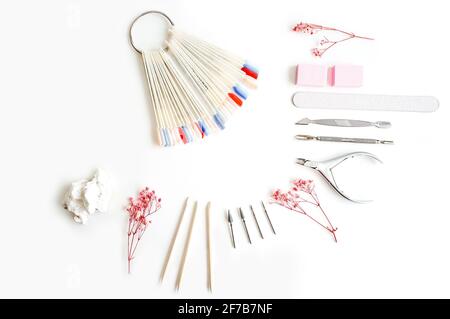 Tools of manicure set and multicolored pallete on white background. Pink flowers as decoration. Stock Photo