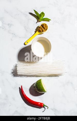 Flat lay of ingredients for thai green curry on white marble background, copy space. Stock Photo