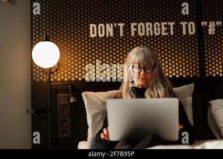 Woman using laptop in hotel bed Stock Photo