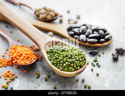Spoons with different types of legumes on a gray concrete background Stock Photo