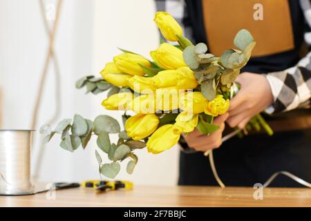 Florist makes a bouquet of fresh yellow tulips. Stock Photo