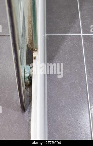 Closeup of the sliding glass door with the lichen and mold stains of the old shower enclosure, selective focus on the mold stain on the splash waterpr Stock Photo