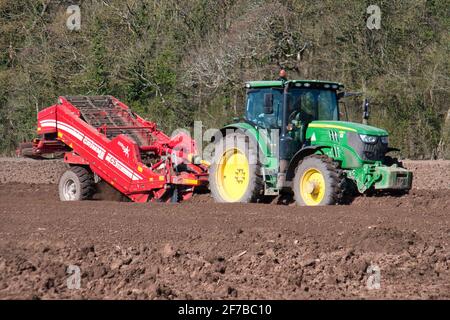 A John Deere tractor towing a Grimme CS150 separator, removing stones and other materials from potato planting beds on a furrowed field in Wirral, UK Stock Photo