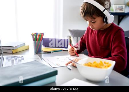 Boy doing homework during breakfast Stock Photo