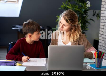 Front view of boy learning with his mother at home Stock Photo