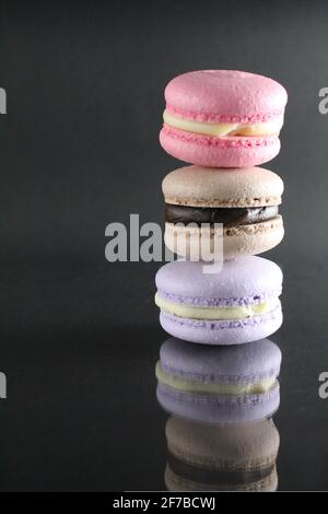 three macaroon brown pink cakes on a black glossy background with a place for text and copyspace. Stock Photo