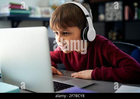 Concentrated boy in headphones in front of laptop Stock Photo