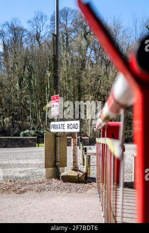 Private road closed with red and white automatic security barrier gate. Automated closure with street sign warning barriers close automatically no Stock Photo