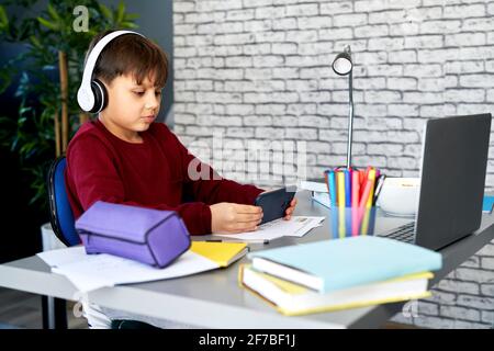 Boy playing on the mobile phone during online classes Stock Photo