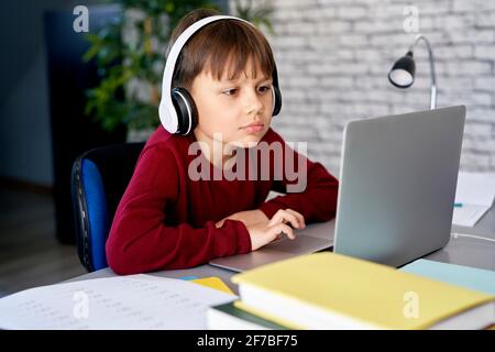 Concentrated boy in headphones while studying at home Stock Photo