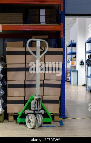 A pallet stacked with boxes ready to be shipped out. A pallet truck is sitting under the pallet to ready move it. Warehouse, despatch, shipping, parce Stock Photo