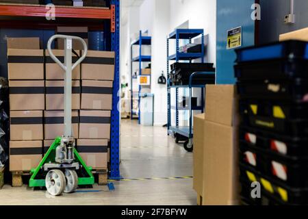 A pallet stacked with boxes ready to be shipped out. A pallet truck is sitting under the pallet to ready move it. Warehouse, despatch, shipping, parce Stock Photo