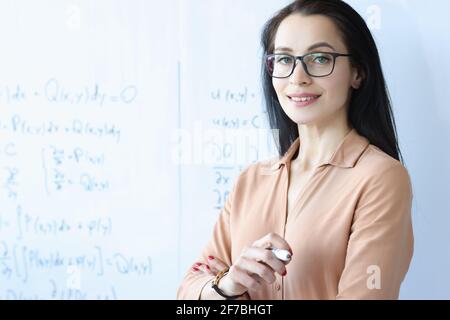 Woman teacher with glasses stands near white board Stock Photo