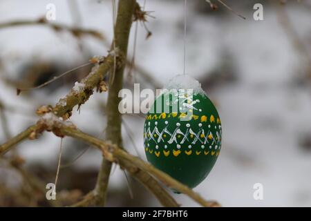 cold and snowy easter holidays with colored and painted hanging easter eggs covered with snow Stock Photo