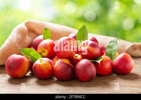 fresh ripe nectarines with leaves on a wooden table in a garden Stock Photo