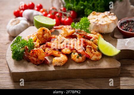grilled shrimps with lime and parsley on a wooden board Stock Photo