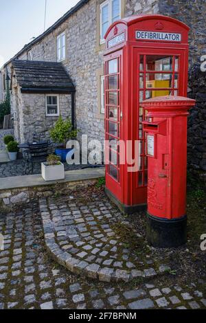 The village telephone kiosk re-purposed as a defibrillator point beside the postbox at Taddington, Peak District National Park, Derbyshire Stock Photo