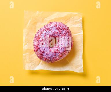 pink donut on yellow paper background, top view Stock Photo