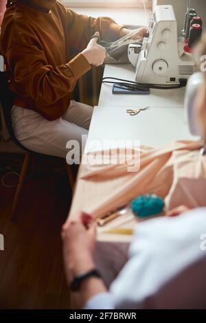 Person near window reaching to thread with crafting scissors Stock Photo
