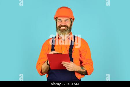 manual worker in helmet. worker with the folder in construction uniform. engineer man with sketches of construction project in folder. Management Stock Photo