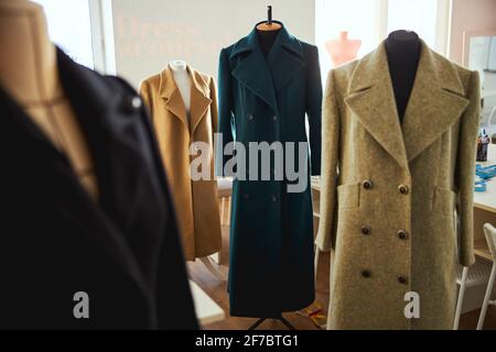 Coats of various colours hanging on tailor busts Stock Photo