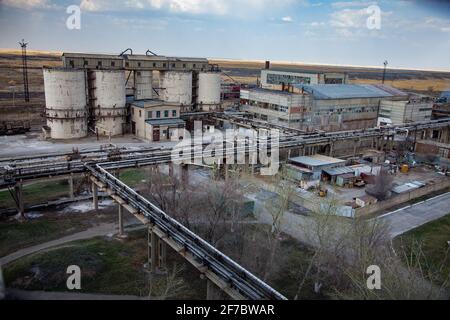 Outdated Soviet mining and processing plant. Concrete elevator and industrial building. Stock Photo