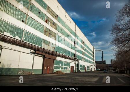 Outdated Soviet mining and processing plant. Industrial building and smoke stack with pollution. Stock Photo