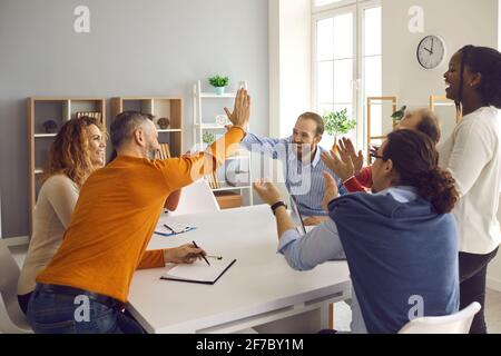 Two teams of happy diverse business people making a deal, high fiving and applauding Stock Photo