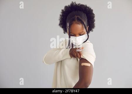 Young woman showing arm with adhesive plaster after getting vaccinated for coronavirus Stock Photo