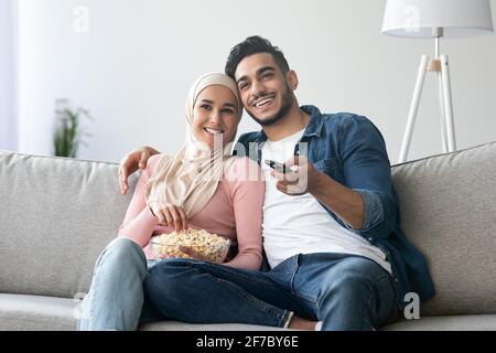 Happy muslim family watching TV together at home Stock Photo