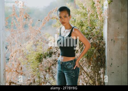 Cheerful young woman with hands on hip wearing sports bra against clear sky  stock photo